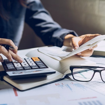 Individual using a calculator and looking at a sheet of paper