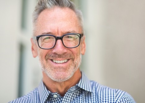 Smiling man with plaid shirt and glasses