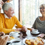 Group of adults smiling while eating lunch at restaurant