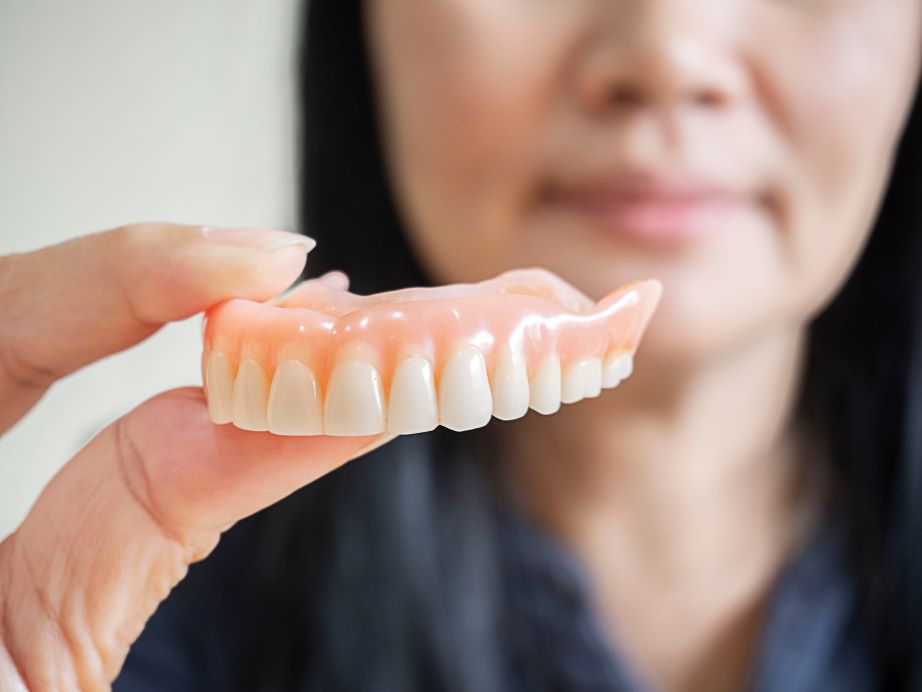 A woman holding a denture