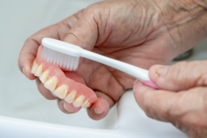 Close up of person brushing their denture