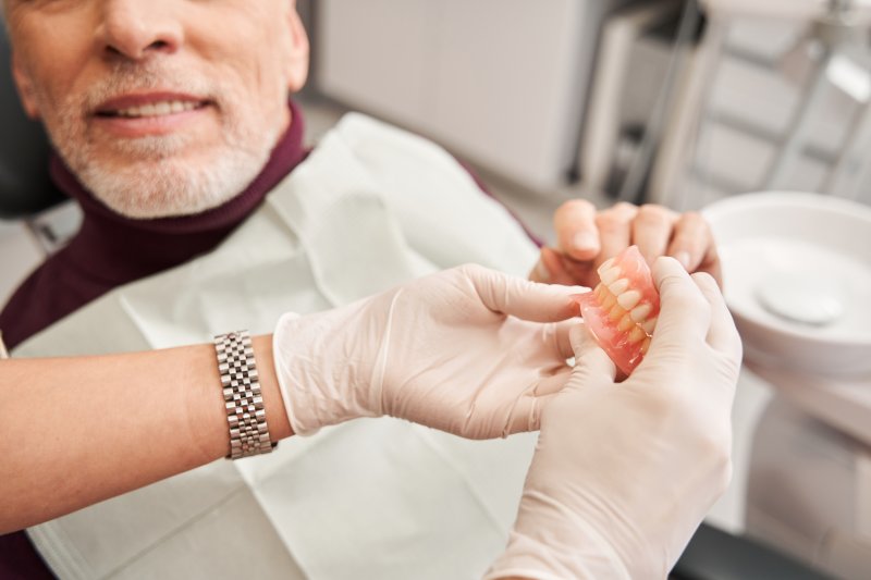 A dentist showing dentures to an older man